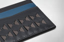 Black leather wallet with geometric pattern and yellow stripe on a light gray background