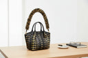 Black handbag with gold pattern and decorative handle on a white background